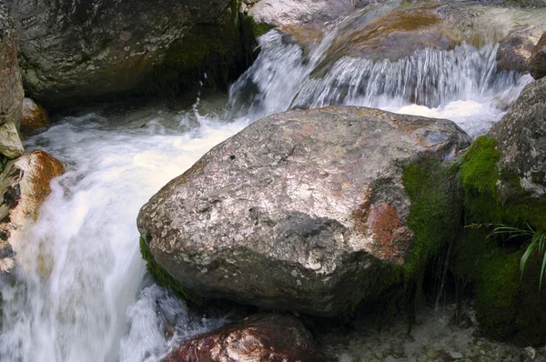 Kleiner Wasserfall neben bemoosten Steinen. — Stockfoto