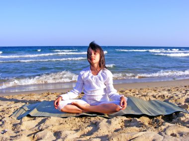 Young girl- meditating on the beach clipart