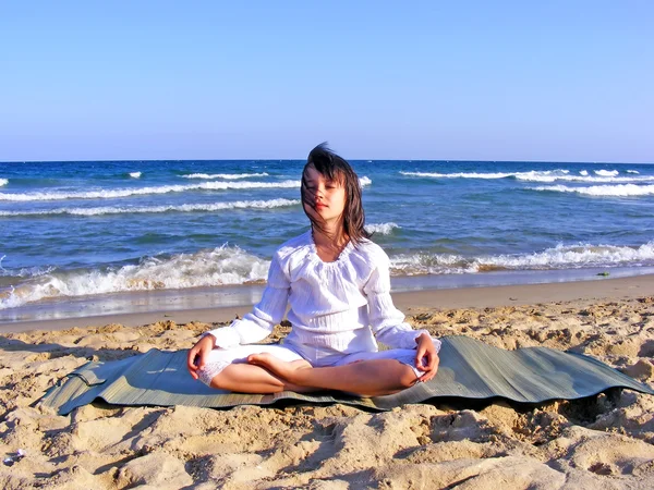 Chica joven meditando en la playa — Foto de Stock