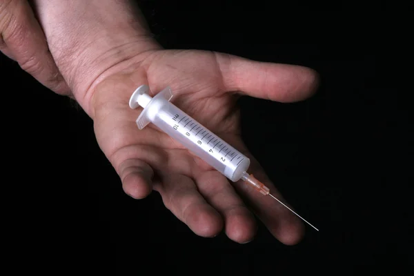 Homem segura injeção na palma da mão — Fotografia de Stock