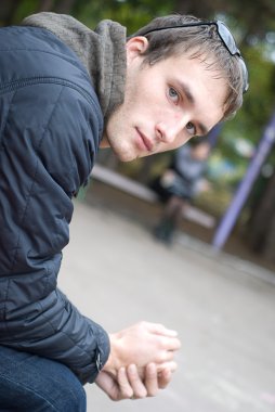 Young handsome sad man seating on bench clipart