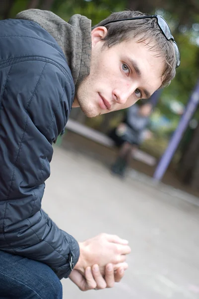 Young handsome sad man seating on bench — Stock Photo, Image