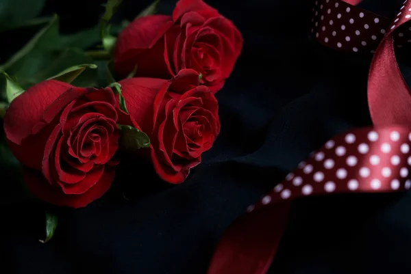 Три красных розы и горящие свечи — стоковое фото