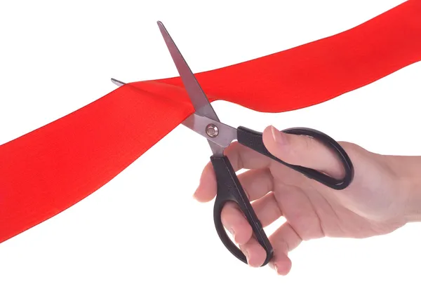 Hand with scissors cutting red ribbon — Stock Photo, Image