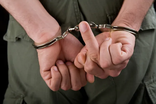 Hands in cuffs showing middle finger — Stock Photo, Image