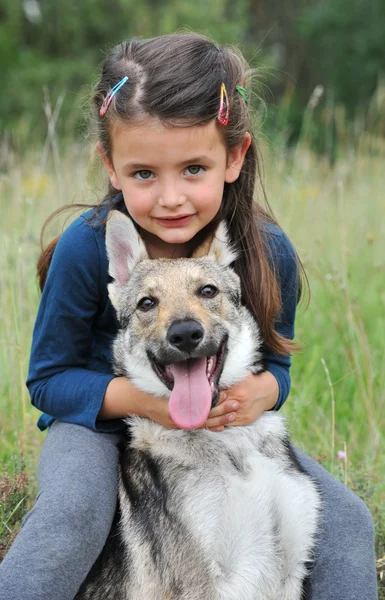 Klein meisje en haar baby wolf hond — Stockfoto