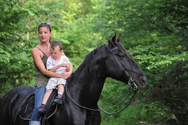 Mãe, filho e cavalo preto — Fotografia de Stock