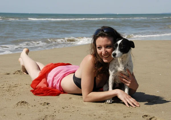 Mujer feliz en la playa con su perro — Foto de Stock