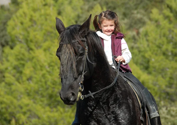 Kleines Mädchen und ihr schwarzes Pferd — Stockfoto