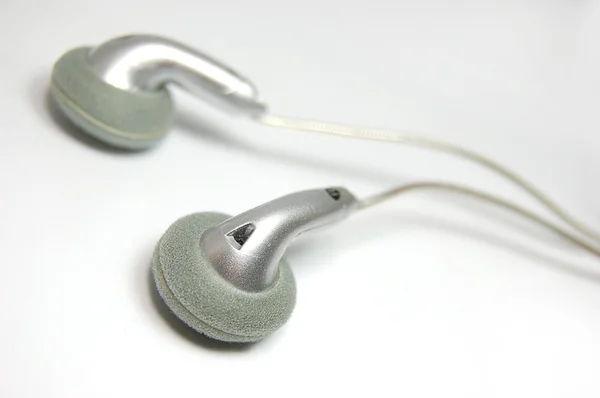 Small metallic headphones on slightly gray background — Stock Photo, Image