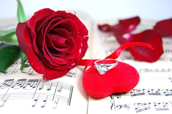 Κόκκινο τριαντάφυλλο και πέταλα σε φύλλο μουσική με ύφασμα καρδιά — Φωτογραφία Αρχείου