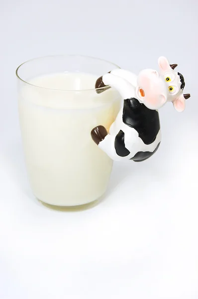 Vaso de leche y vaca de juguete en blanco — Foto de Stock