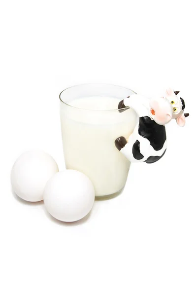 Стакан молока, яиц и игрушечной коровы на белом — стоковое фото
