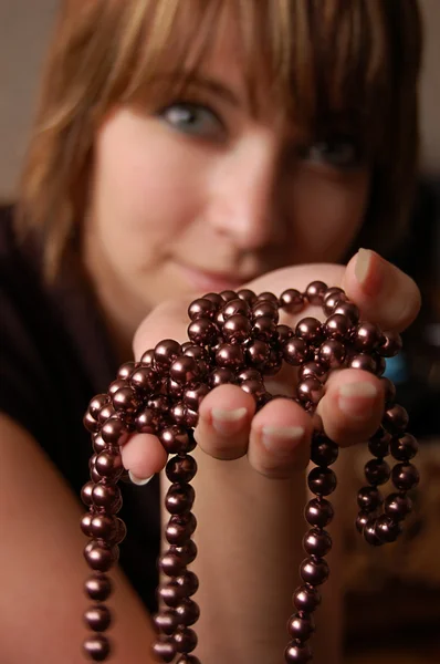 Hnědovlasé děvče dívat se skrz Perlové šperky — Stock fotografie