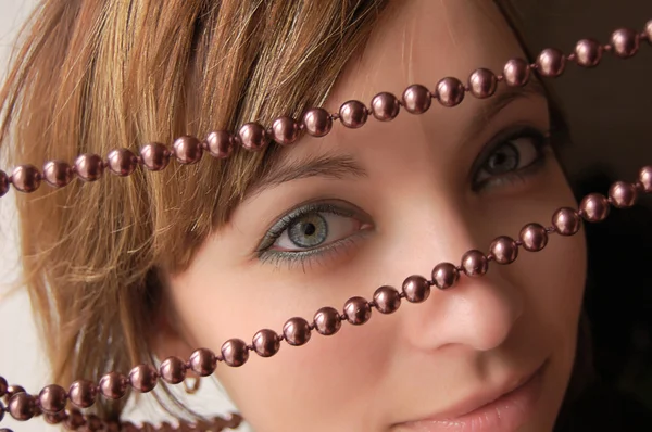 Chica de cabello castaño mirando a través de joyas de perlas —  Fotos de Stock