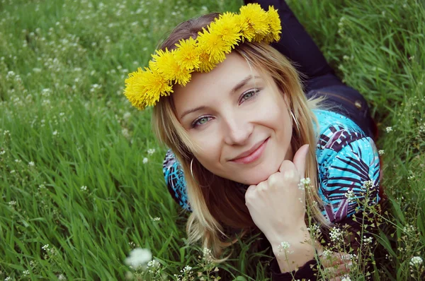 Chica con diadema de diente de león sobre hierba verde —  Fotos de Stock