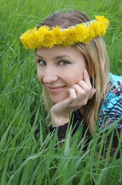 Hermosa chica con diadema de diente de león acostado en hierba verde —  Fotos de Stock