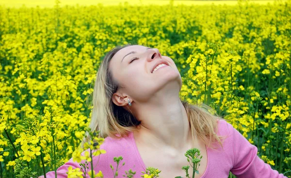 Beautiful girl among blooming rapeseed oilseed field — Stockfoto