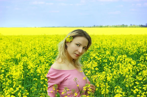 Beautiful girl among blooming rapeseed oilseed field — Stok fotoğraf