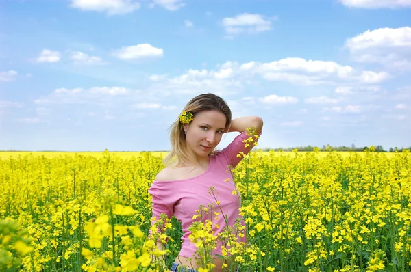 Hermosa chica entre el campo de semillas oleaginosas de colza en flor — Foto de Stock