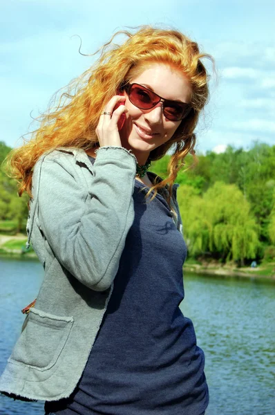 Vrolijk meisje glimlachend en praten over telefoon op aard achtergrond — Stockfoto