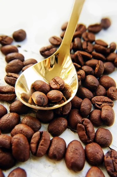Koffiebonen en gouden lepel — Stockfoto