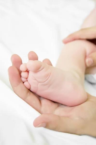 女性手は赤ちゃんの足を保持します。 — ストック写真