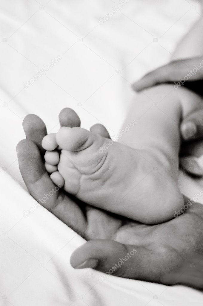 Woman hand holds baby leg