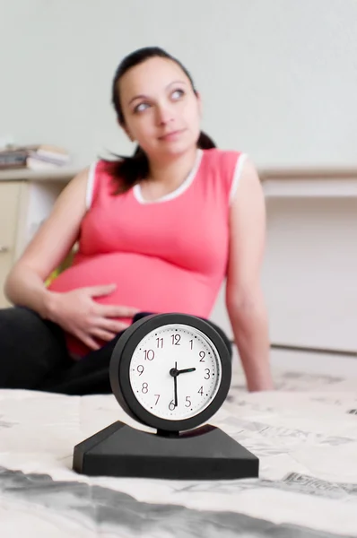 Беременная женщина и часы — стоковое фото