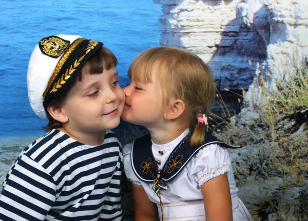 Ragazza baciare un ragazzo in abito marino Immagini Stock Royalty Free