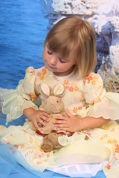 Flicka som leker med en leksak kanin — Stockfoto