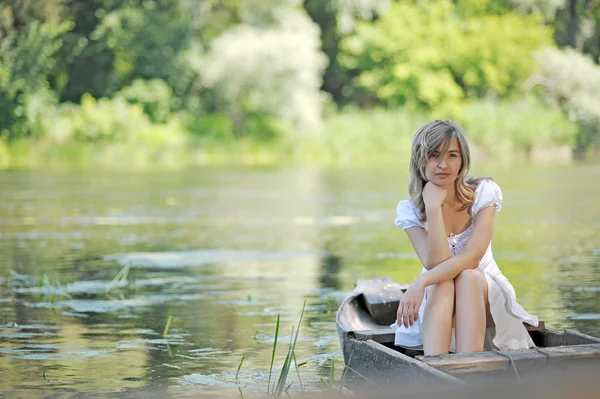 Chica joven en un barco en el río — Stockfoto