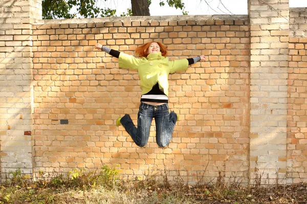 Girl jumps against a brick wall — Stock Photo, Image