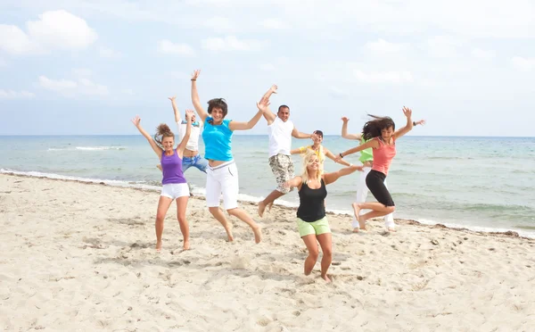 Šťastný posádky skákání na pláži — Stock fotografie