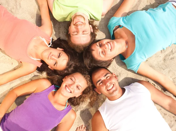 Teens lying on a sandy beach in a circle Stock Photo
