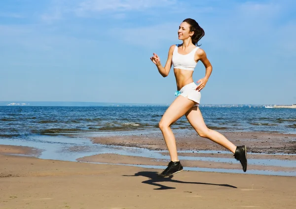 Молода жінка біжить сама на пляжі — стокове фото