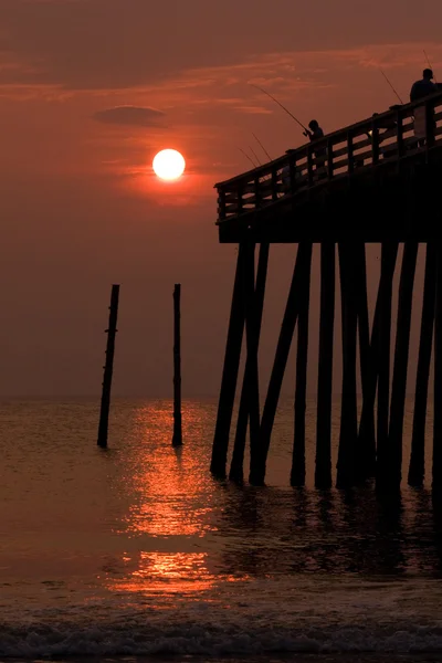 Silhouet van een jongen vissen vanaf een pier — Stockfoto