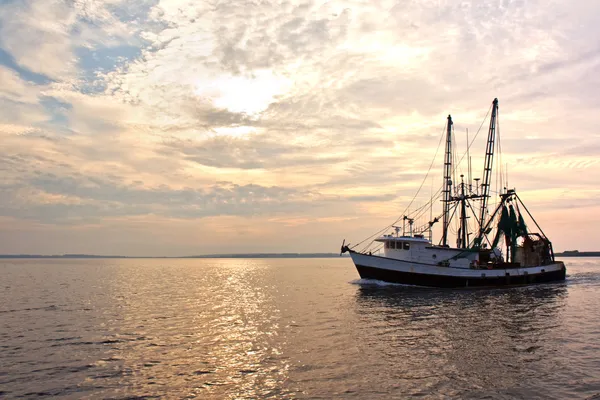 Vonóhálós halászhajó a víz napkeltekor — Stock Fotó