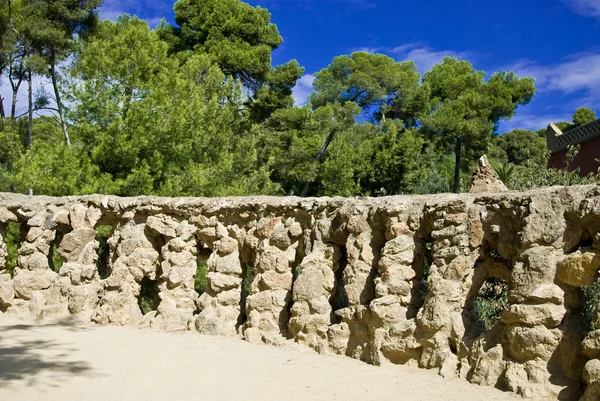 A bricked stone railing styled by antonio gaudi in park guell and a wonderful blue sky — Stock Photo, Image