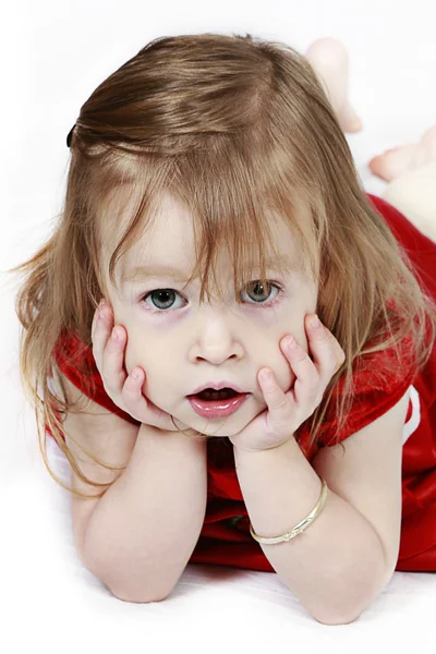 Klein meisje in een rode jurk met handen op gezicht — Stockfoto