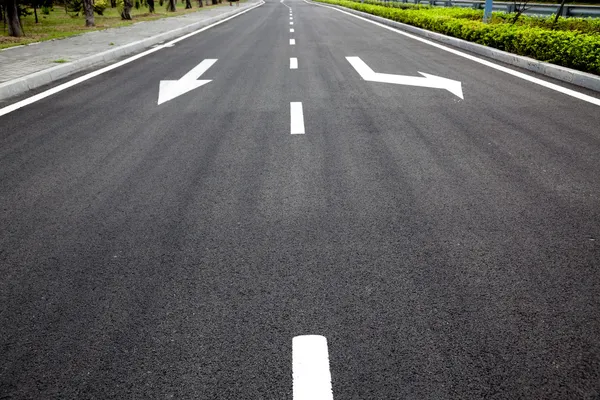 Carretera señaliza flechas en superficie asfaltada —  Fotos de Stock