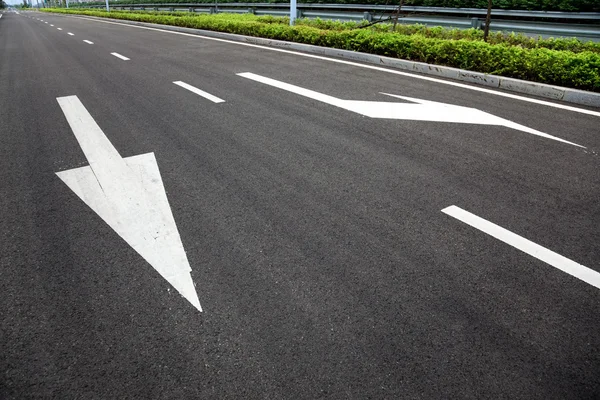Carretera señaliza flechas en superficie asfaltada — Foto de Stock