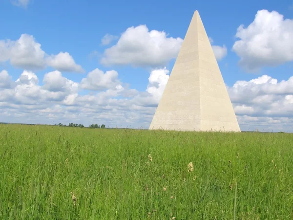 Пирамида стоит на зеленом поле — стоковое фото