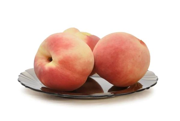 Three peaches on a black plate — Stock Photo, Image