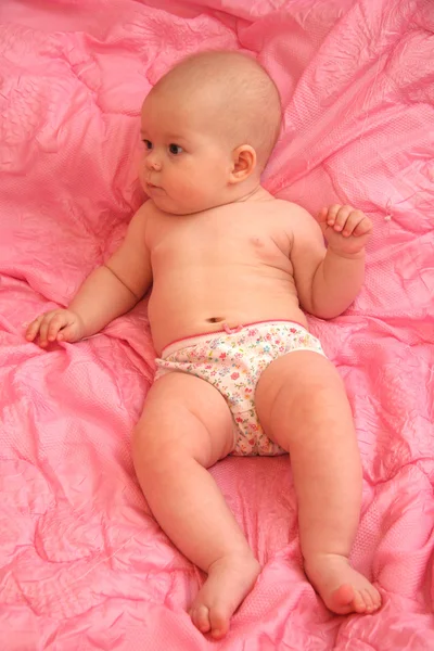 Het kleine meisje op een roze achtergrond — Stockfoto