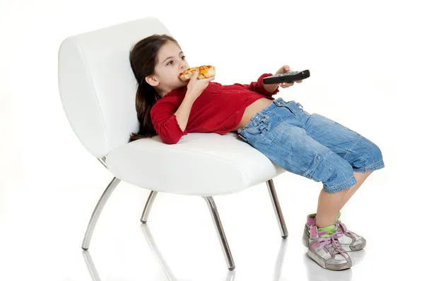 Criança comendo pizza com controle remoto — Fotografia de Stock