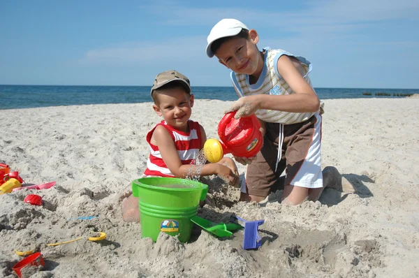 Çocuklar sahilde oyuncaklarla oynuyorlar.