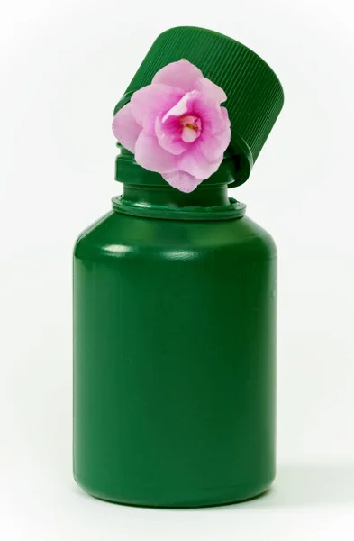 Küçük yeşil şişe ve pembe çiçek — Stok fotoğraf