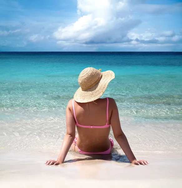 Красивая женщина сидит на берегу моря Лицензионные Стоковые Изображения
