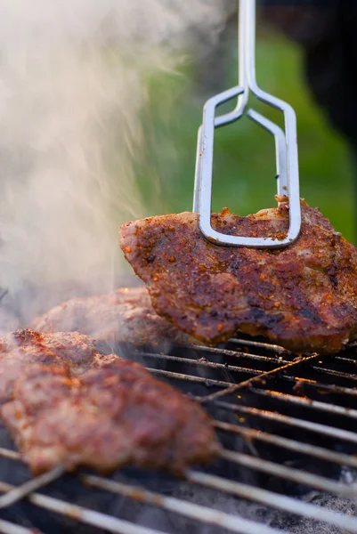 Barbecue detail with metal tongs. — Stock Photo, Image